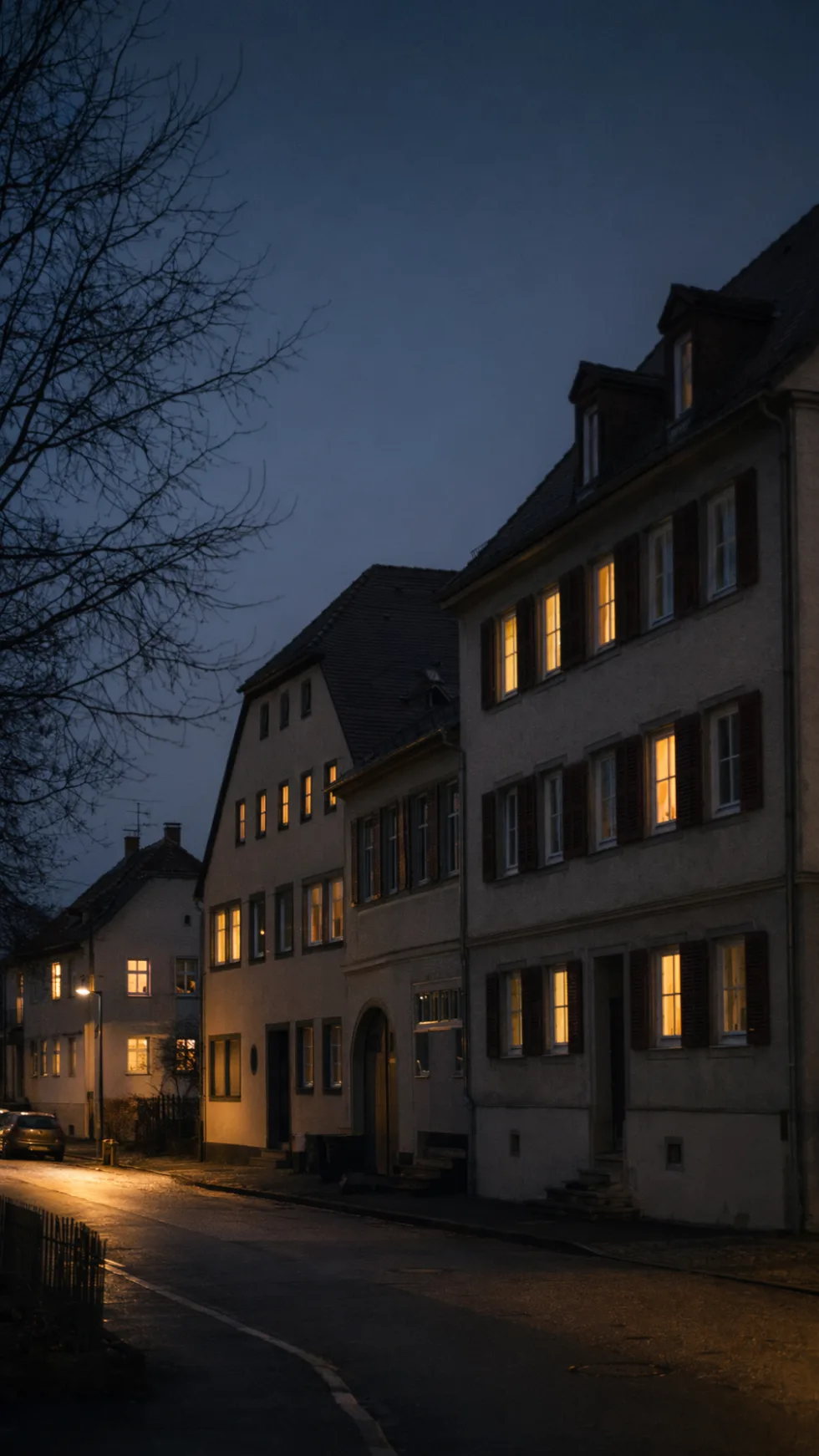 A quiet residential street at blue hour, warm light in the windows
